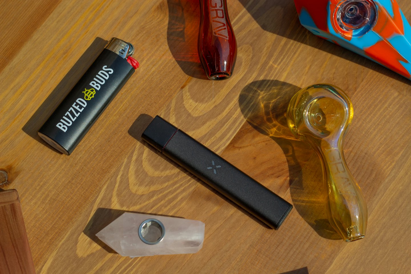 Various smoking pipes and a vape pen on wood.