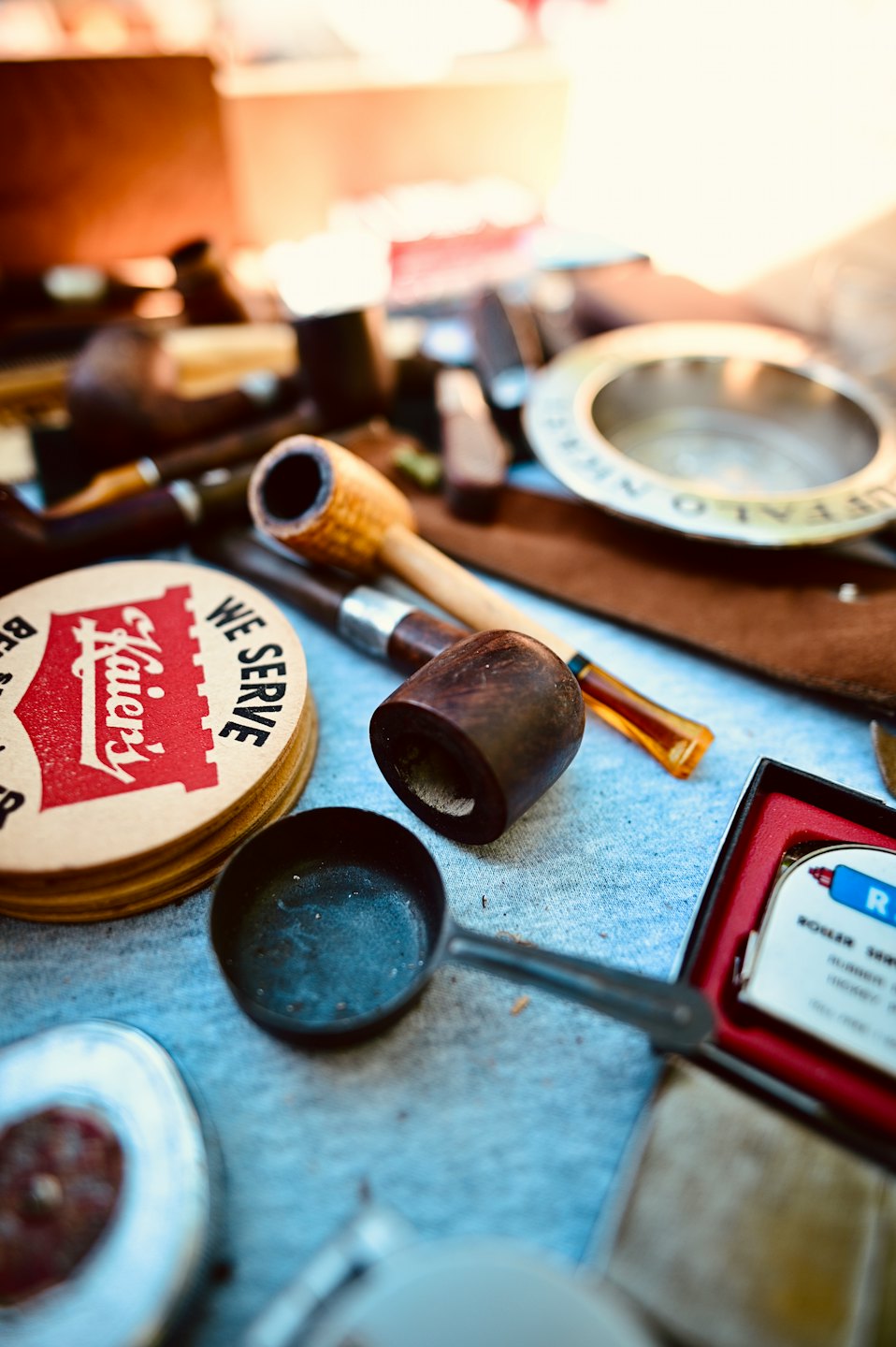 Vintage smoking pipes and coasters displayed on a blue-grey surface.