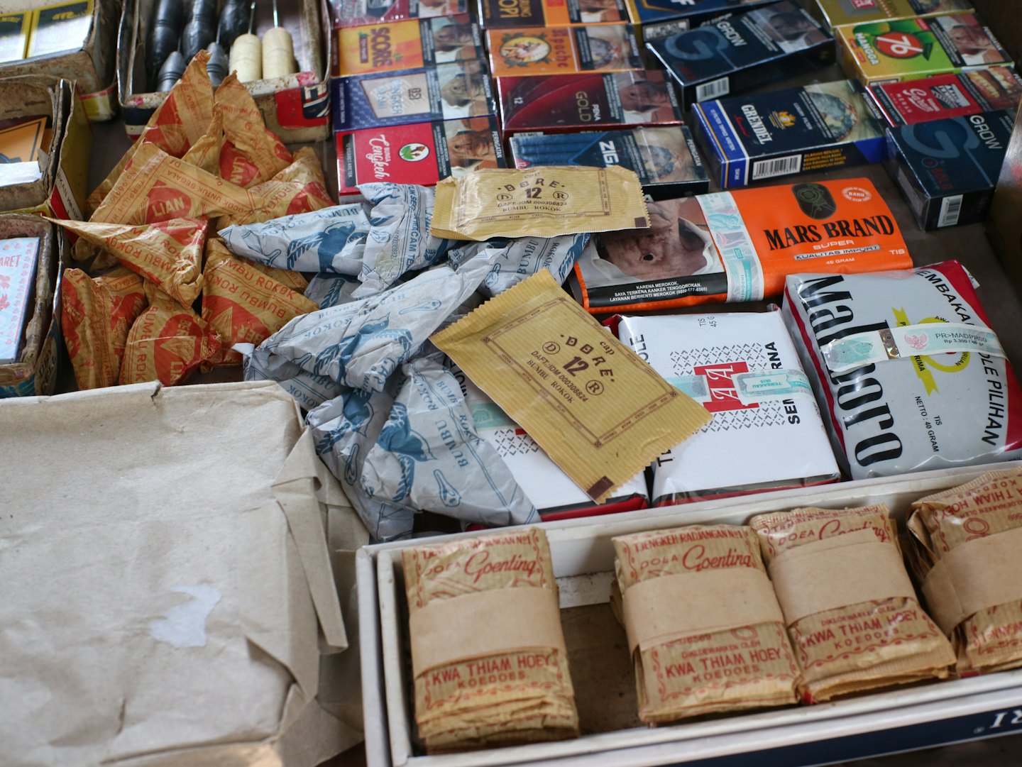Assorted tobacco products and rolling papers on a market stall.